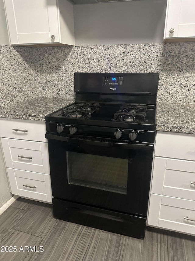 kitchen with light stone counters, white cabinets, and black gas range oven