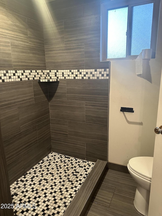 bathroom featuring tiled shower and toilet