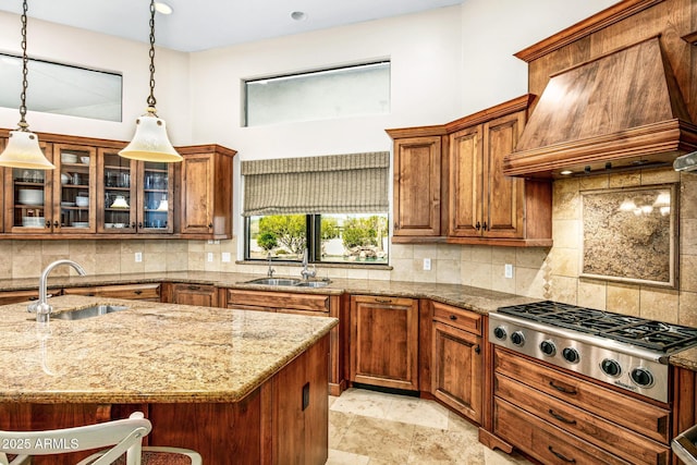 kitchen with a sink, light stone countertops, custom exhaust hood, and stainless steel gas cooktop