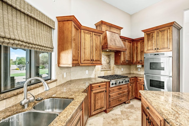 kitchen with backsplash, appliances with stainless steel finishes, custom range hood, and a sink