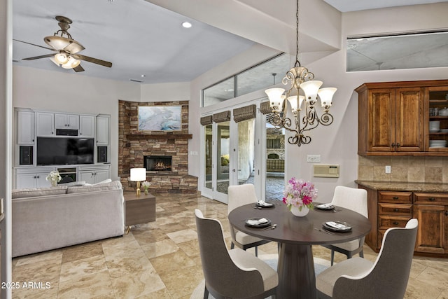 dining space featuring a fireplace and ceiling fan with notable chandelier