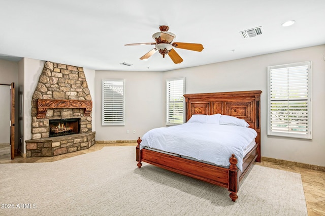 bedroom featuring visible vents, multiple windows, and a stone fireplace