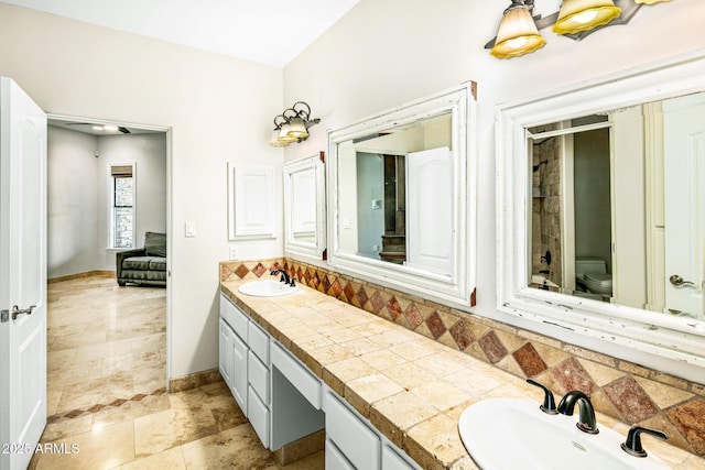 full bath with a sink, tasteful backsplash, toilet, and double vanity