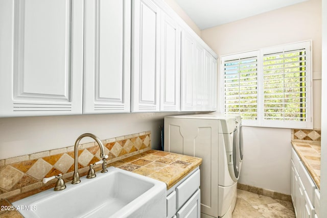 laundry room featuring a sink, cabinet space, baseboards, and washer and clothes dryer