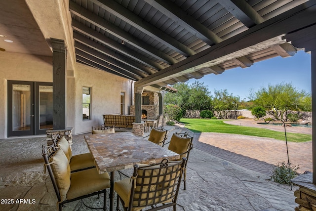 view of patio with outdoor dining area, a fenced backyard, and an outdoor stone fireplace