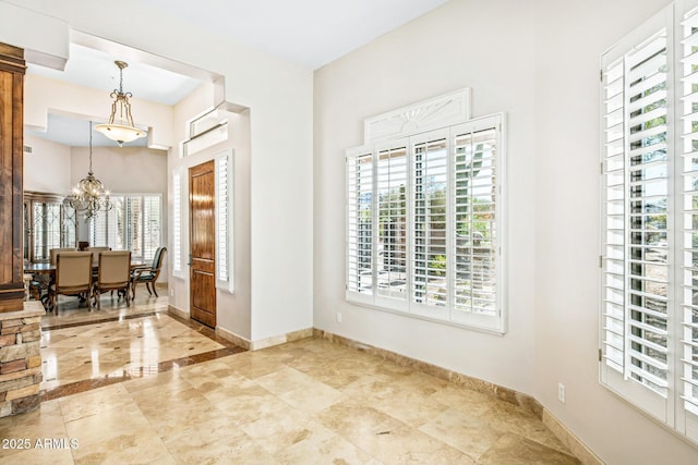 entryway featuring a notable chandelier and baseboards