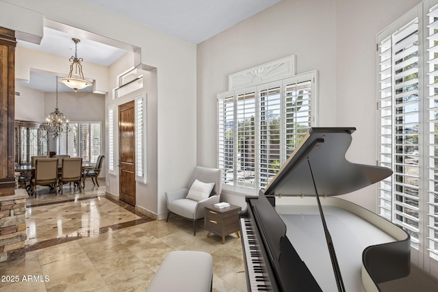 living area featuring a notable chandelier, baseboards, and marble finish floor