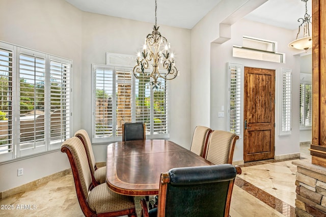 dining space featuring a wealth of natural light, a notable chandelier, and baseboards