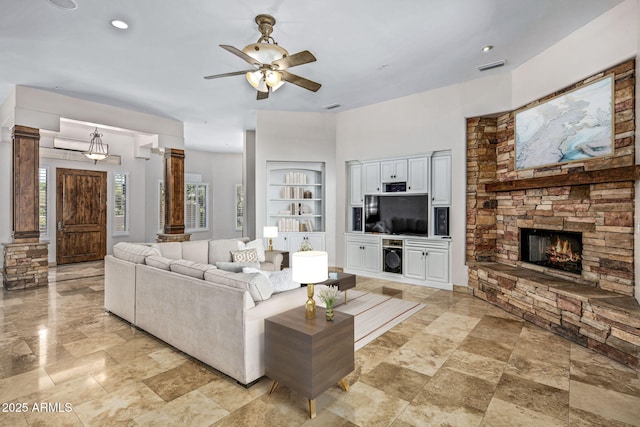 living area with visible vents, ceiling fan, built in features, a fireplace, and ornate columns