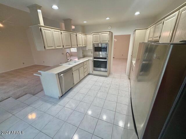 kitchen with light carpet, stainless steel appliances, and sink