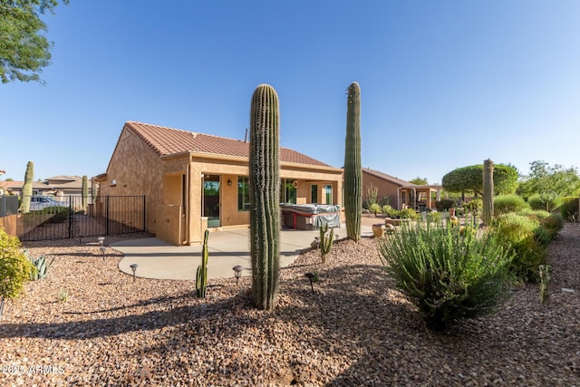7504 W Patriot Way, Florence, AZ 85132 - back of property featuring a hot tub, a patio area, a tile roof, stucco siding, and a gate