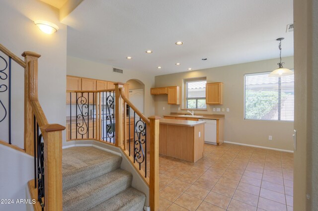 kitchen with light brown cabinets, a kitchen island, decorative light fixtures, and white appliances