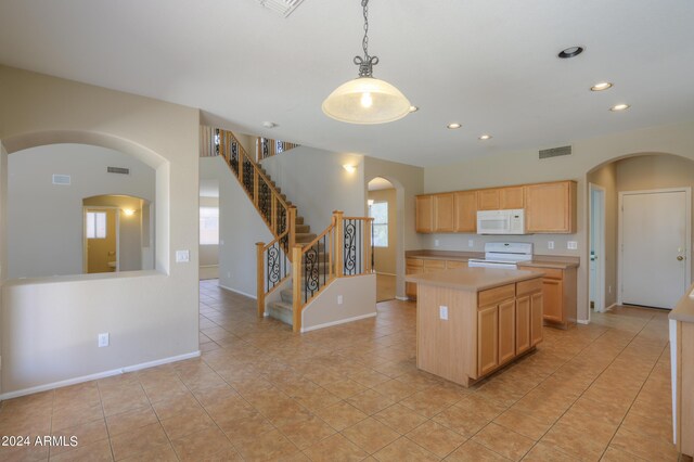 kitchen featuring a stone fireplace, a center island, light tile patterned floors, and hanging light fixtures