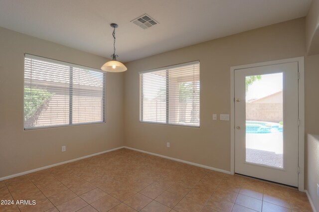 unfurnished room featuring plenty of natural light, light colored carpet, and a notable chandelier