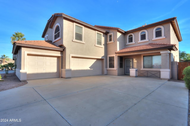 view of front of property featuring a garage, concrete driveway, a tiled roof, and stucco siding