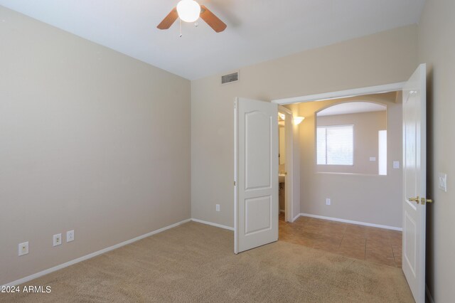 empty room with ceiling fan and light carpet