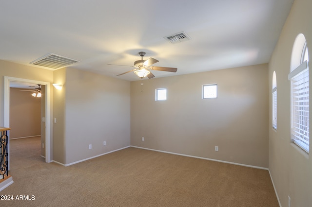 empty room featuring ceiling fan and light colored carpet