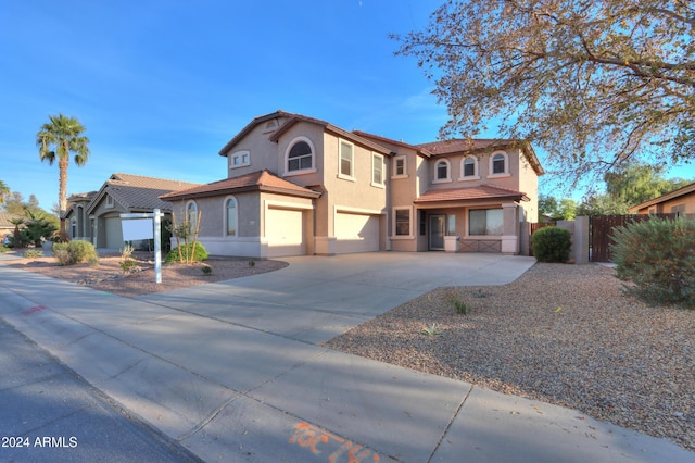 view of front of property featuring stucco siding, an attached garage, a gate, fence, and driveway