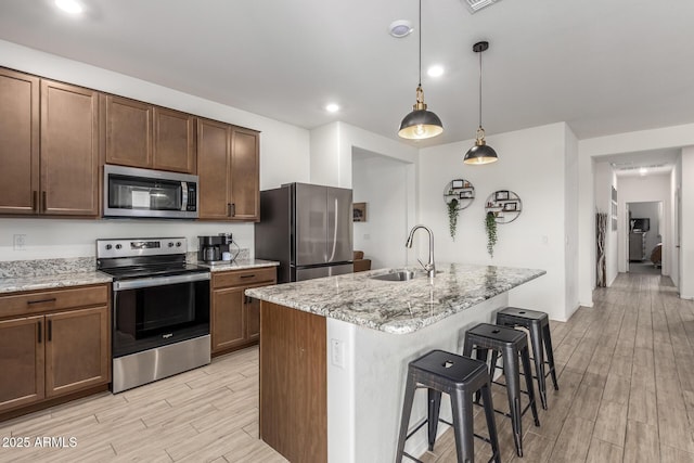 kitchen with hanging light fixtures, an island with sink, appliances with stainless steel finishes, and sink