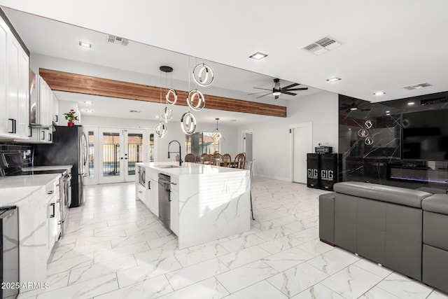 kitchen with pendant lighting, sink, white cabinets, a large island, and french doors