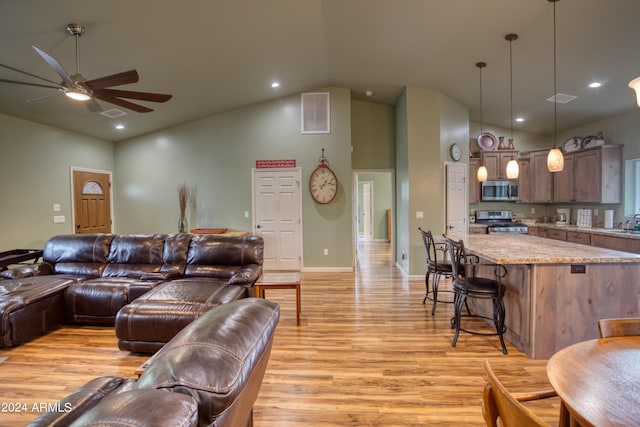 living room with ceiling fan, light hardwood / wood-style floors, and high vaulted ceiling