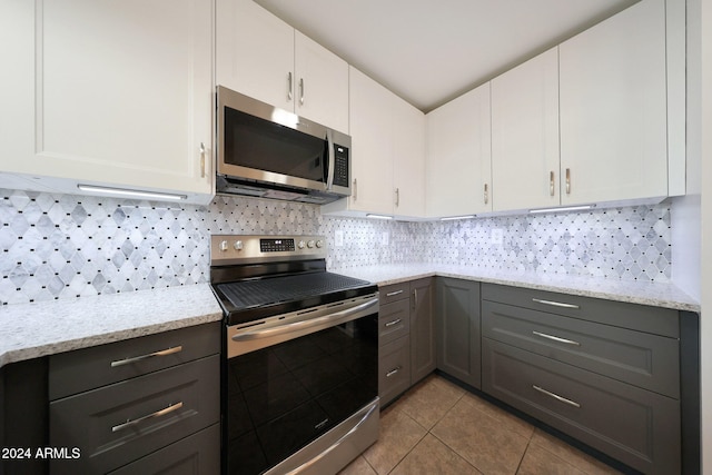 kitchen featuring backsplash, white cabinets, light tile patterned flooring, and appliances with stainless steel finishes