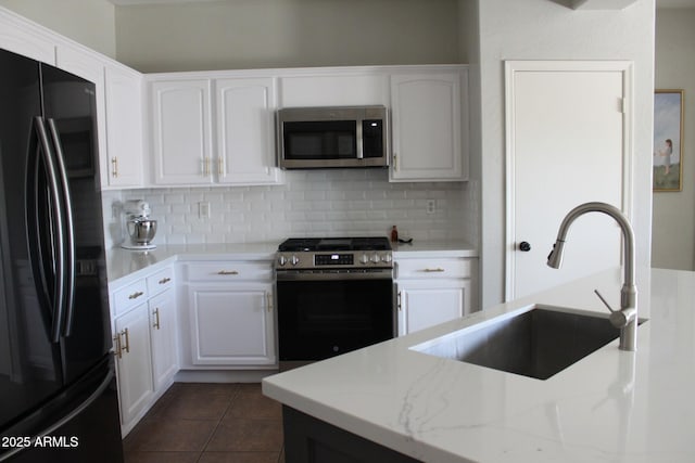 kitchen featuring sink, white cabinetry, stainless steel appliances, dark tile patterned flooring, and decorative backsplash