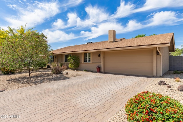 single story home with decorative driveway, a garage, stucco siding, and a chimney