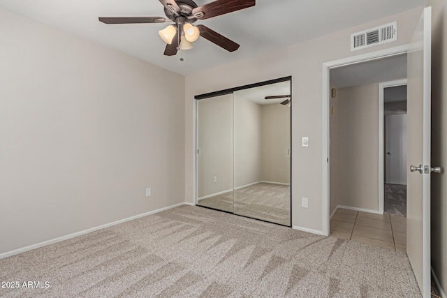 unfurnished bedroom featuring a ceiling fan, visible vents, carpet floors, baseboards, and a closet