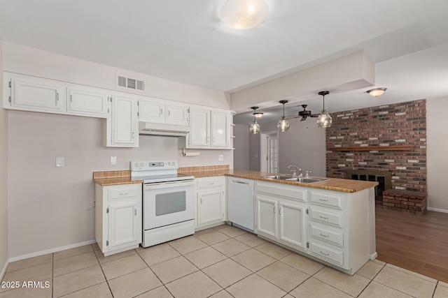 kitchen featuring a sink, white appliances, a peninsula, white cabinetry, and visible vents