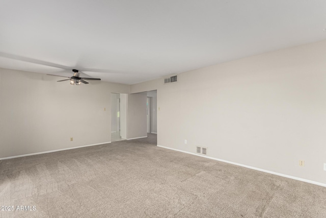 carpeted spare room featuring baseboards, visible vents, and ceiling fan