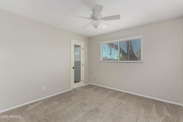 carpeted spare room with a ceiling fan and baseboards