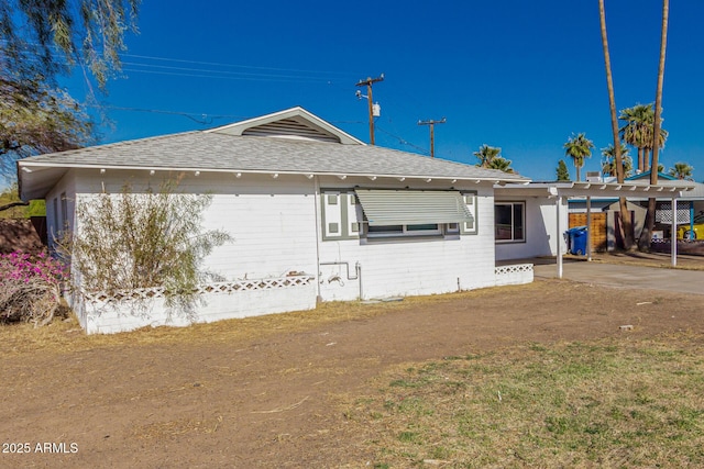 exterior space with an attached carport and roof with shingles