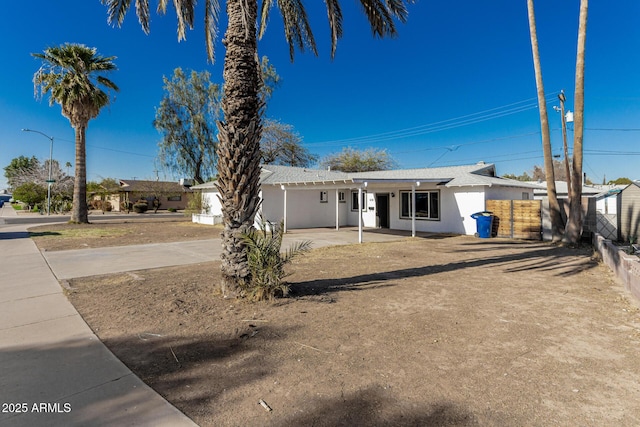 ranch-style home featuring fence and stucco siding