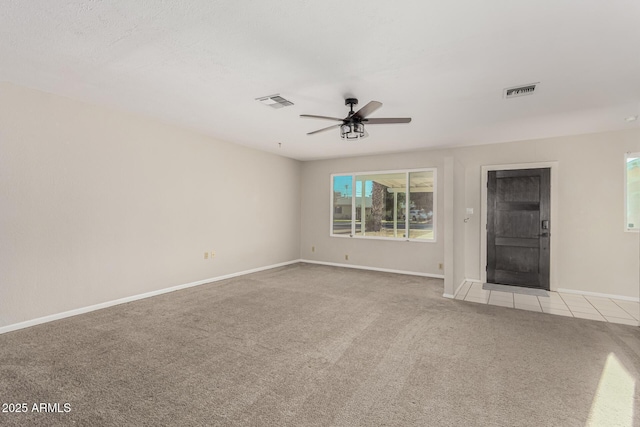 empty room featuring a ceiling fan, light colored carpet, visible vents, and baseboards