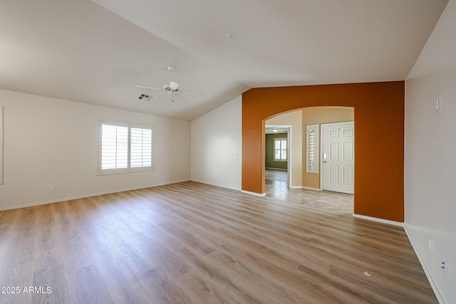 spare room with arched walkways, ceiling fan, vaulted ceiling, and a healthy amount of sunlight