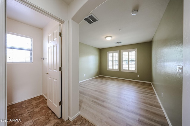 unfurnished room with baseboards, plenty of natural light, and visible vents