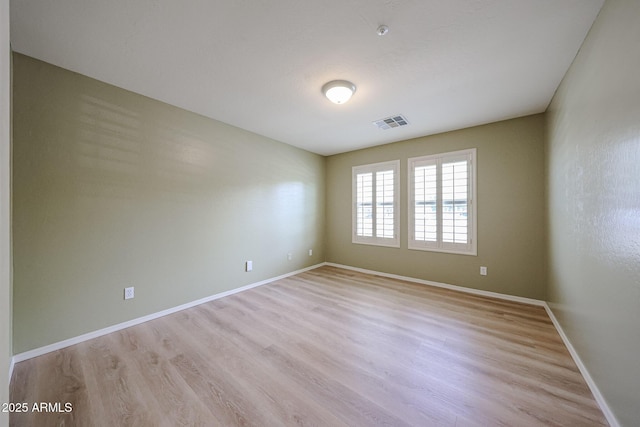 spare room with visible vents, light wood finished floors, and baseboards