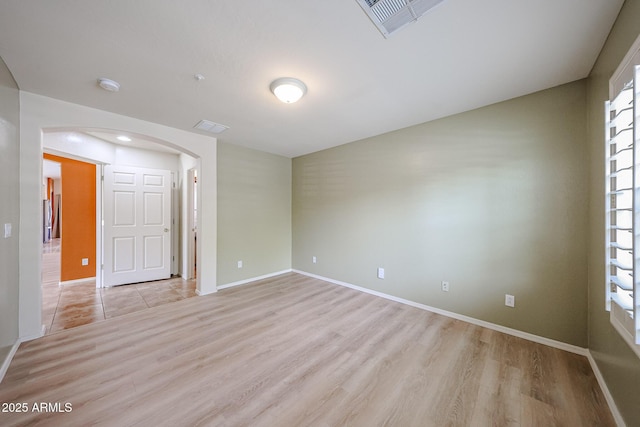 unfurnished room with arched walkways, baseboards, light wood-type flooring, and visible vents