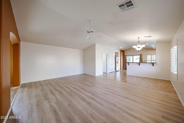 unfurnished living room with arched walkways, lofted ceiling, light wood finished floors, and visible vents