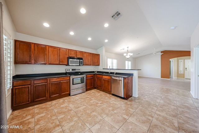 kitchen featuring dark countertops, appliances with stainless steel finishes, a peninsula, vaulted ceiling, and visible vents