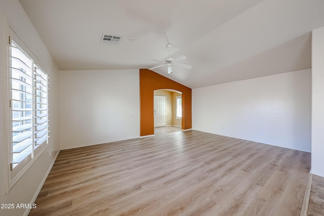 empty room featuring visible vents, arched walkways, light wood finished floors, and ceiling fan