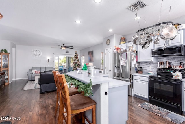 kitchen with a breakfast bar, white cabinets, decorative backsplash, appliances with stainless steel finishes, and a kitchen island