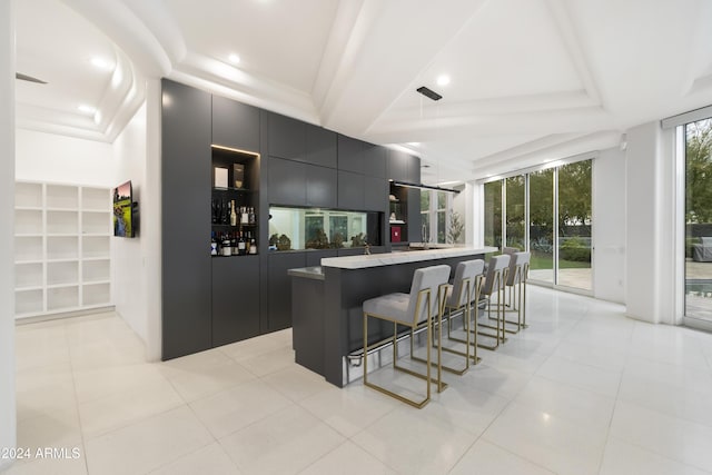 kitchen featuring a breakfast bar area, a raised ceiling, light tile patterned floors, and decorative light fixtures