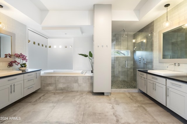 bathroom with a stall shower, tasteful backsplash, a sink, a garden tub, and two vanities