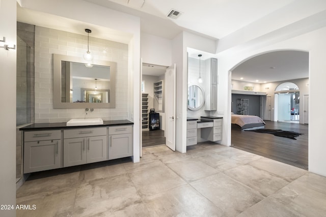 ensuite bathroom with a walk in closet, visible vents, decorative backsplash, vanity, and ensuite bath