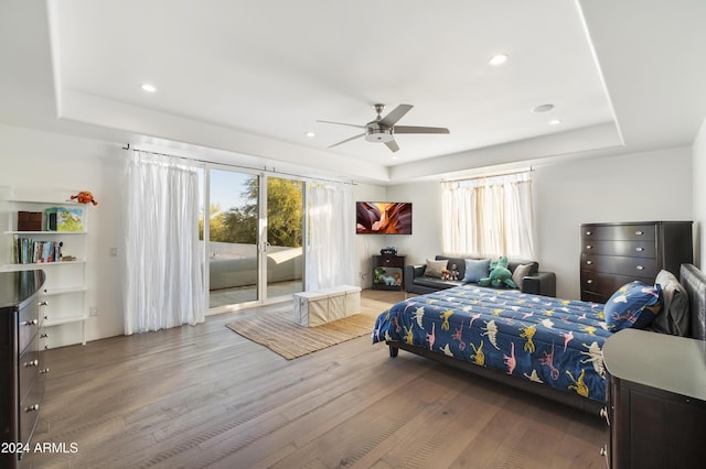 bedroom featuring access to exterior, hardwood / wood-style floors, a raised ceiling, and ceiling fan