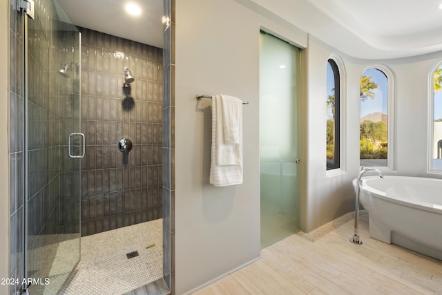 bathroom featuring a freestanding tub, a shower stall, baseboards, and wood finished floors