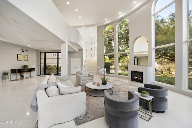 tiled living room with a high ceiling, stairway, a glass covered fireplace, and recessed lighting