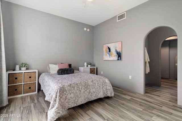 bedroom featuring arched walkways, visible vents, ceiling fan, and wood finished floors